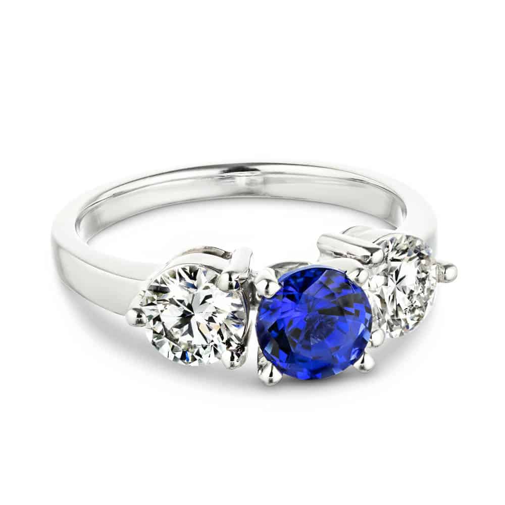 Shown with Round Cut Lab Grown Diamonds on either side of a Lab Created Blue Sapphire in 14k White Gold|Three stone engagement with round cut lab grown diamonds and lab created blue sapphire center stone in 14k white gold