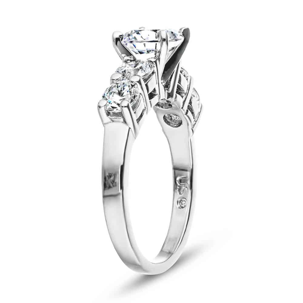 Shown with a 1ct Round Cut Lab Grown Diamond Center Stone amid four 0.25ct Diamond Hybrids in 14k White Gold|Accented engagement ring with a 1ct round cut lab grown diamond amid diamond hybrid simulants totaling 1ctw in 14k white gold shown from side