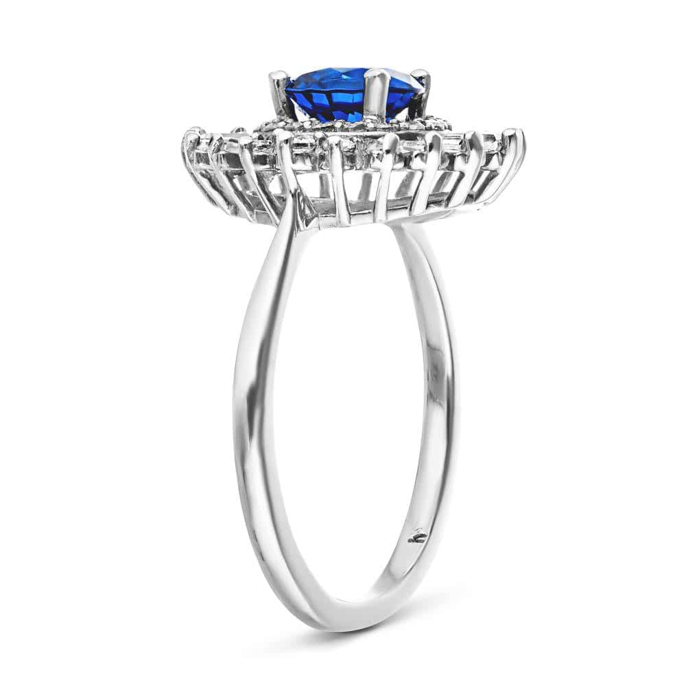 Shown with 1ct Round Cut Lab Grown Blue Sapphire|Unique stunning vintage style diamond halo engagement ring with baguette cut diamonds surrounding a 1ct round cut lab grown blue sapphire in 14k white gold shown from side