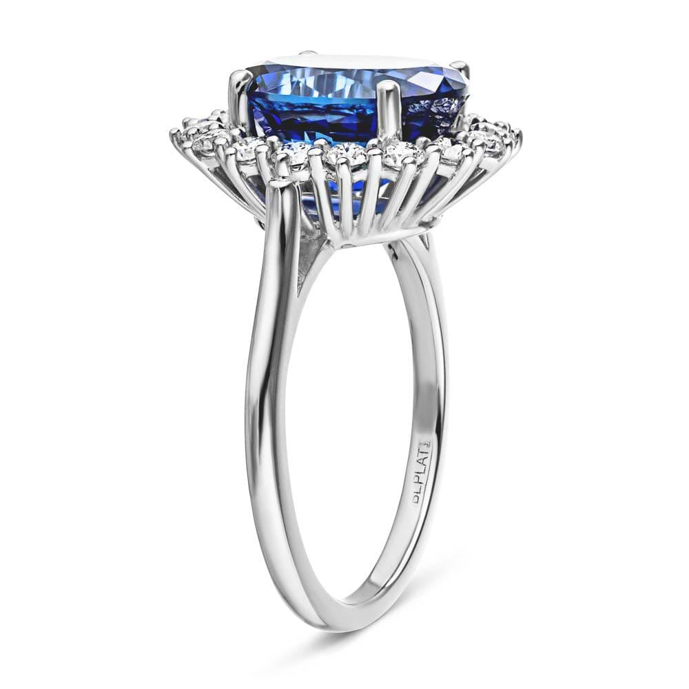 Shown with 3ct Oval Cut Lab Grown Blue Sapphire in 14k White Gold|Vintage style engagement ring with floral design halo around a 3ct lab created blue sapphire in 14k white gold shown from side