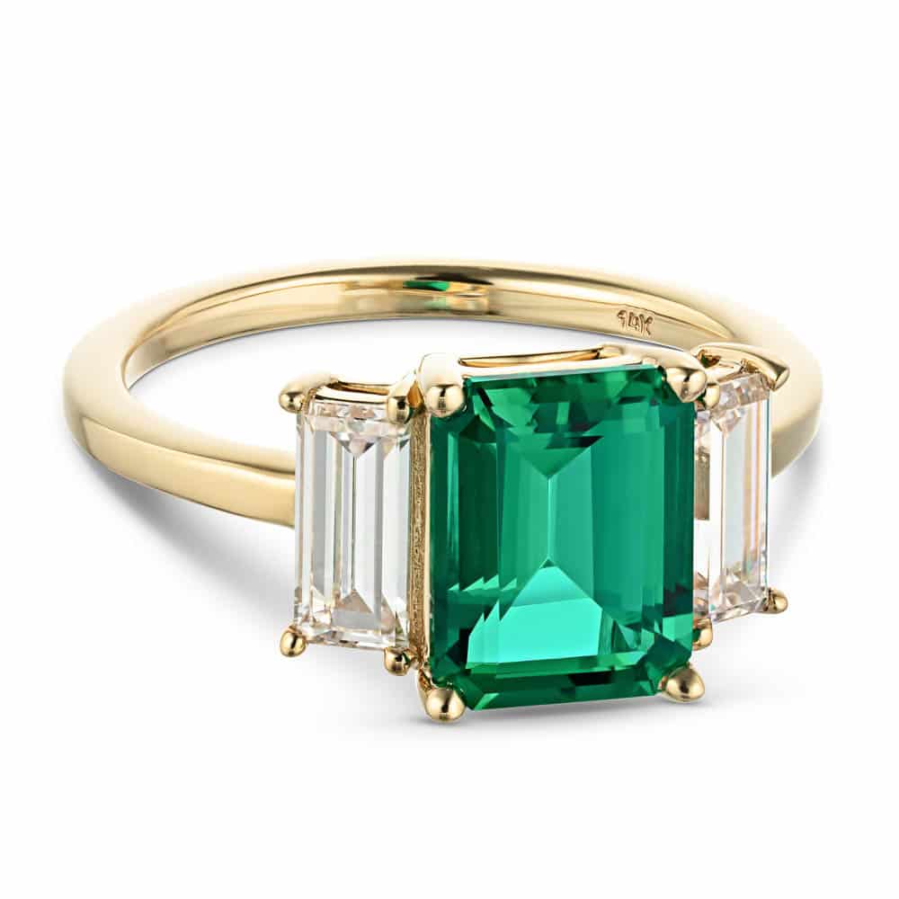 Shown with 2ct Emerald Cut Lab Grown Emerald with 2 Baguette Cut Lab Diamonds in 14k Yellow Gold|Gorgeous three stone engagement ring with 2ct emerald cut lab created emerald center between baguette cut lab diamonds set in 14k yellow gold