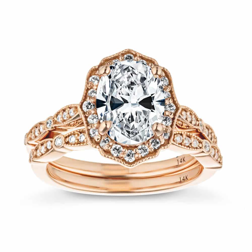 Shown with 1ct Oval Cut Lab Created Diamond in 14k Rose Gold with Matching Wedding Band|Vintage style rose gold wedding ring set inspired by Paris design featuring filigree detailing around diamond accented band and halo with a 1ct oval cut lab grown diamond