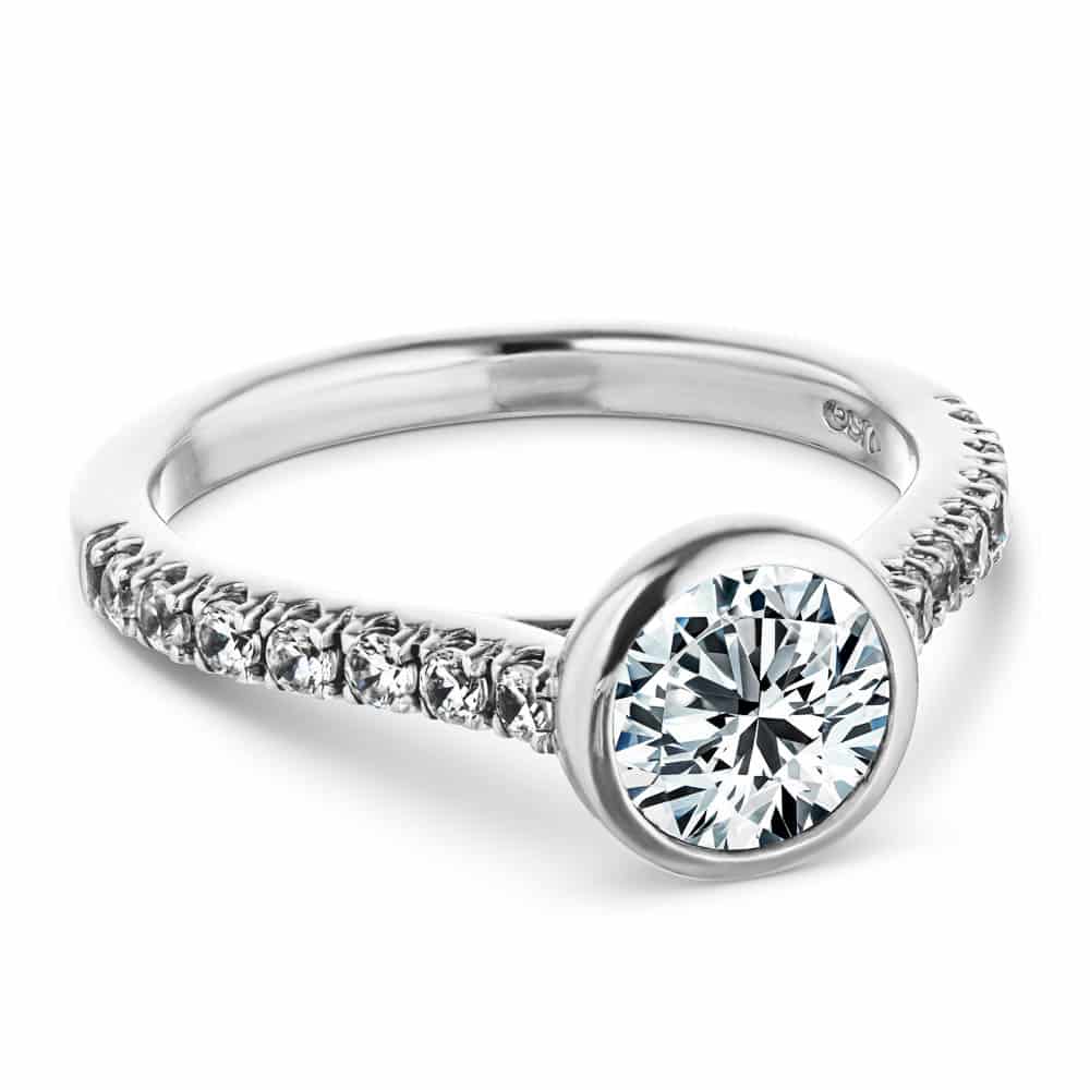 Shown with a bezel set 1.0ct Round cut Lab-Grown Diamond with accenting stones on the band in recycled 14K white gold | stackable engagement ring Shown with a bezel set 1.0ct Round cut Lab-Grown Diamond with accenting stones on the band in recycled 14K white gold