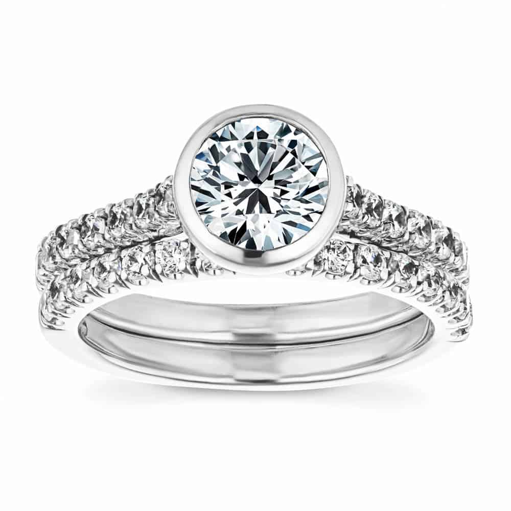 Shown with the matching wedding band | stackable engagement ring Shown with a bezel set 1.0ct Round cut Lab-Grown Diamond with accenting stones on the band in recycled 14K white gold with matching wedding band