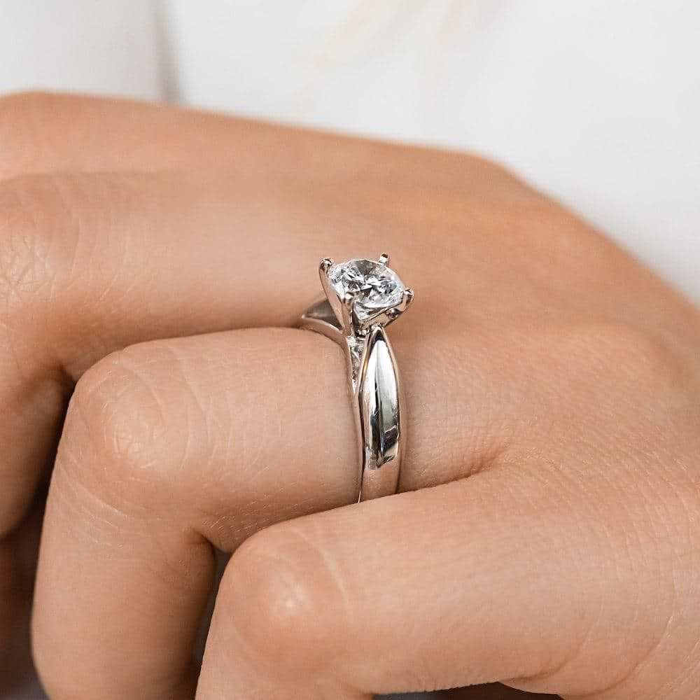 Shown with 1ct Round Cut Lab Grown Diamond in Platinum|Modern solitaire engagement ring with wide band and cathedral style design featuring 1ct round cut lab grown diamond in platinum worn on hand