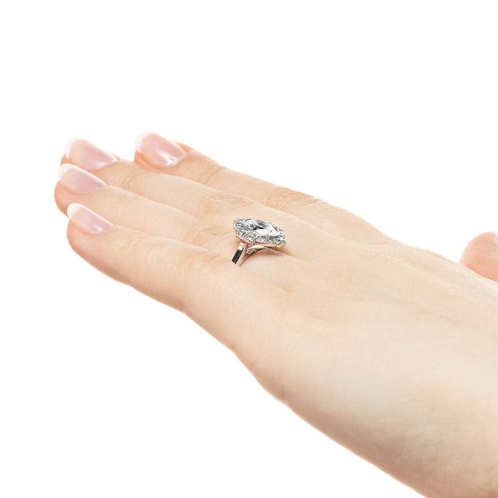 Shown with 1ct Oval Cut Lab Grown Diamond in 14k White Gold|Vintage style engagement ring with milgrain detail diamond accented halo surrounding 1ct oval cut lab grown diamond in 14k white gold shown worn on hand sideview