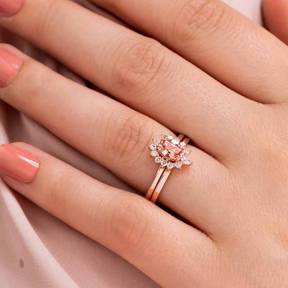Engagement Ring shown with matching Wedding Band completing the diamond halo, available as a set for a discount|Vintage style beautiful engagement ring with half halo and a 1ct oval cut lab grown champagne pink sapphire in 14 yellow gold worn on hand with matching wedding band