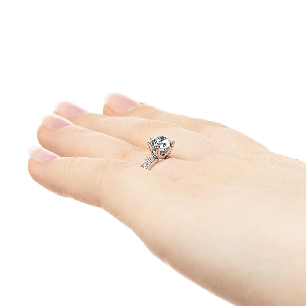 Shown with 1ct Round Cut Lab Grown Diamond in 14k White Gold|Channel set diamond accented engagement ring with 1ct round cut lab grown diamond in 14k white gold worn on hand sideview