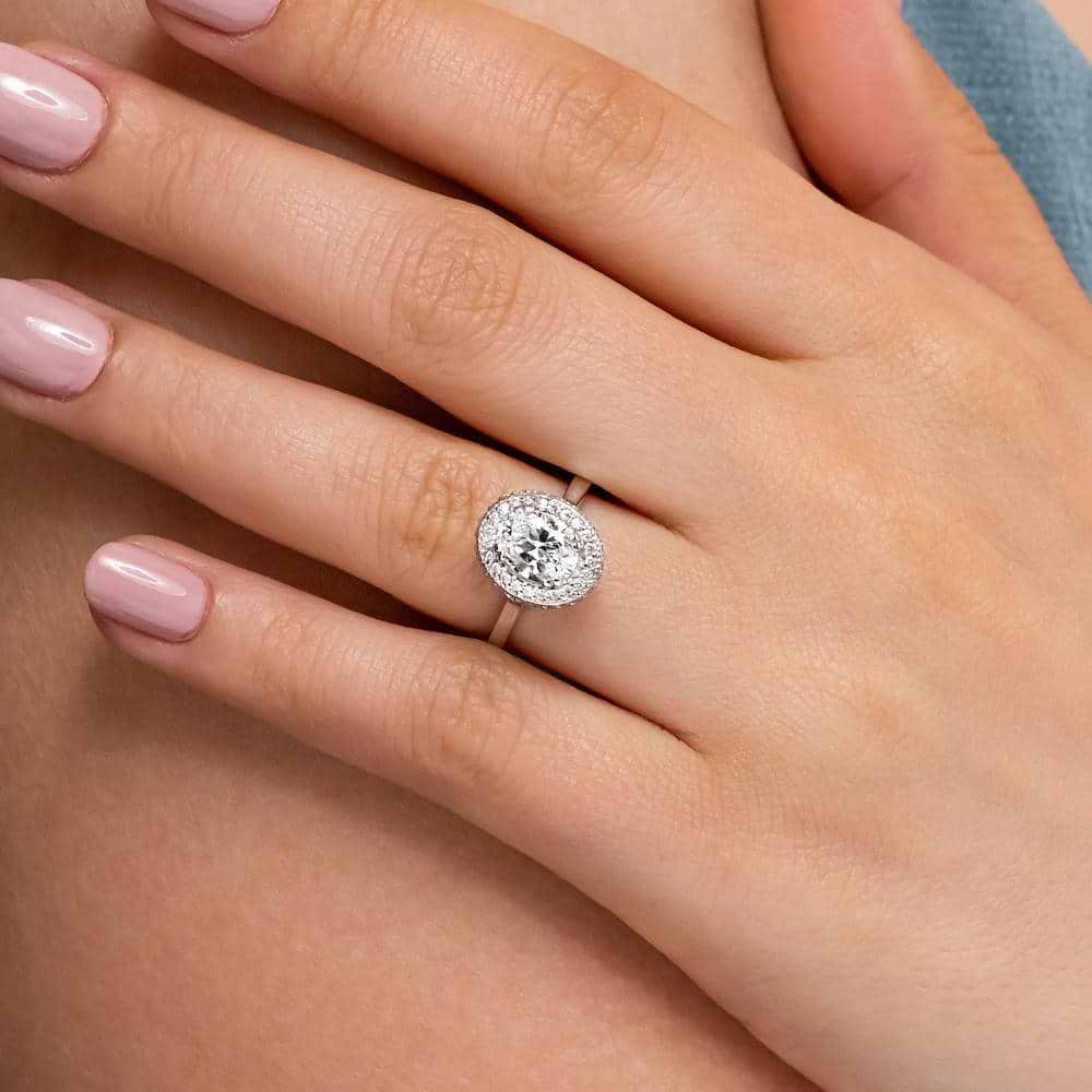 Shown with 1ct Oval Cut Lab Grown Diamond in 14k White Gold|Antique style diamond accented halo engagement ring with 1ct oval cut lab grown diamond in 14k white gold shown worn on hand