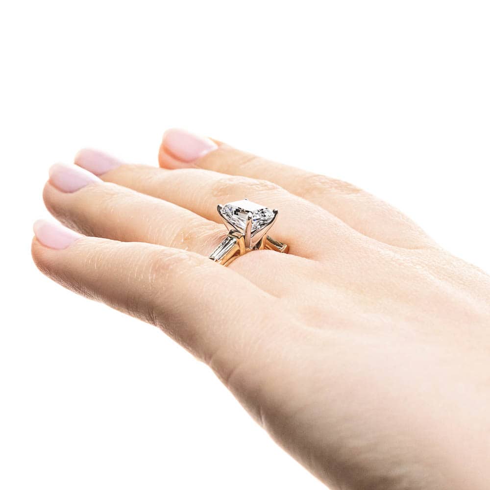 Shown with 1.5ct Emerald Cut Lab Grown Diamond in 14k Yellow Gold|Modern three stone engagement ring with two baguette cut recycled diamond side stones and a 1.5ct emerald cut lab grown diamond center in 14k yellow gold worn on hand