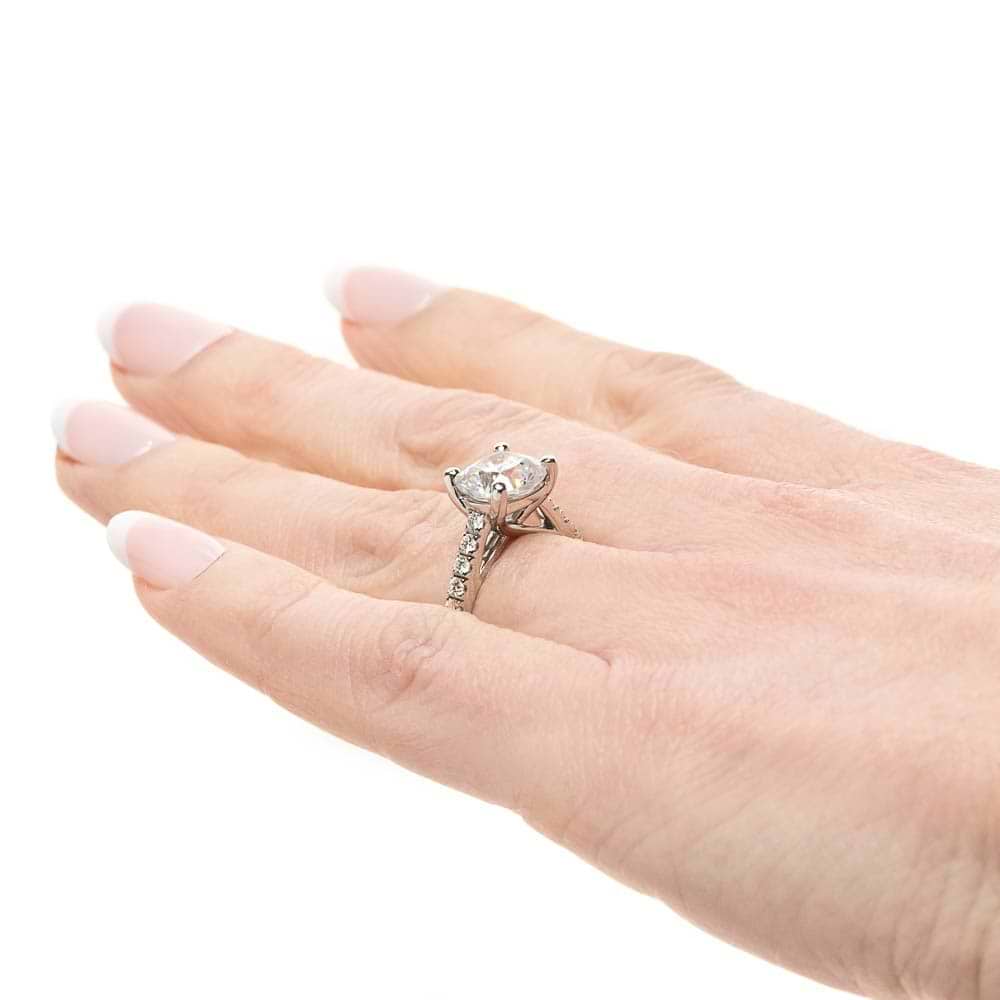 Shown with 1ct Cushion Cut Lab Grown Diamond in Platinum|Diamond accented engagement ring with 1ct cushion cut lab grown diamond set in a four prong trellis in platinum worn on hand sideview