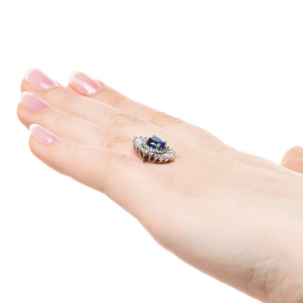 Shown with 1ct Round Cut Lab Grown Blue Sapphire|Unique stunning vintage style diamond halo engagement ring with baguette cut diamonds surrounding a 1ct round cut lab grown blue sapphire in 14k white gold worn on hand sideview