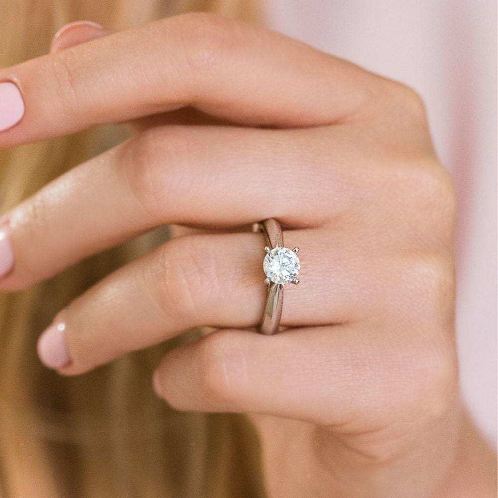 Shown with 1ct Round Cut Lab Grown Diamond in 14k White Gold|Simple solitaire engagement ring with cathedral design holding a 1ct round cut lab grown diamond in 14k white gold shown worn on hand