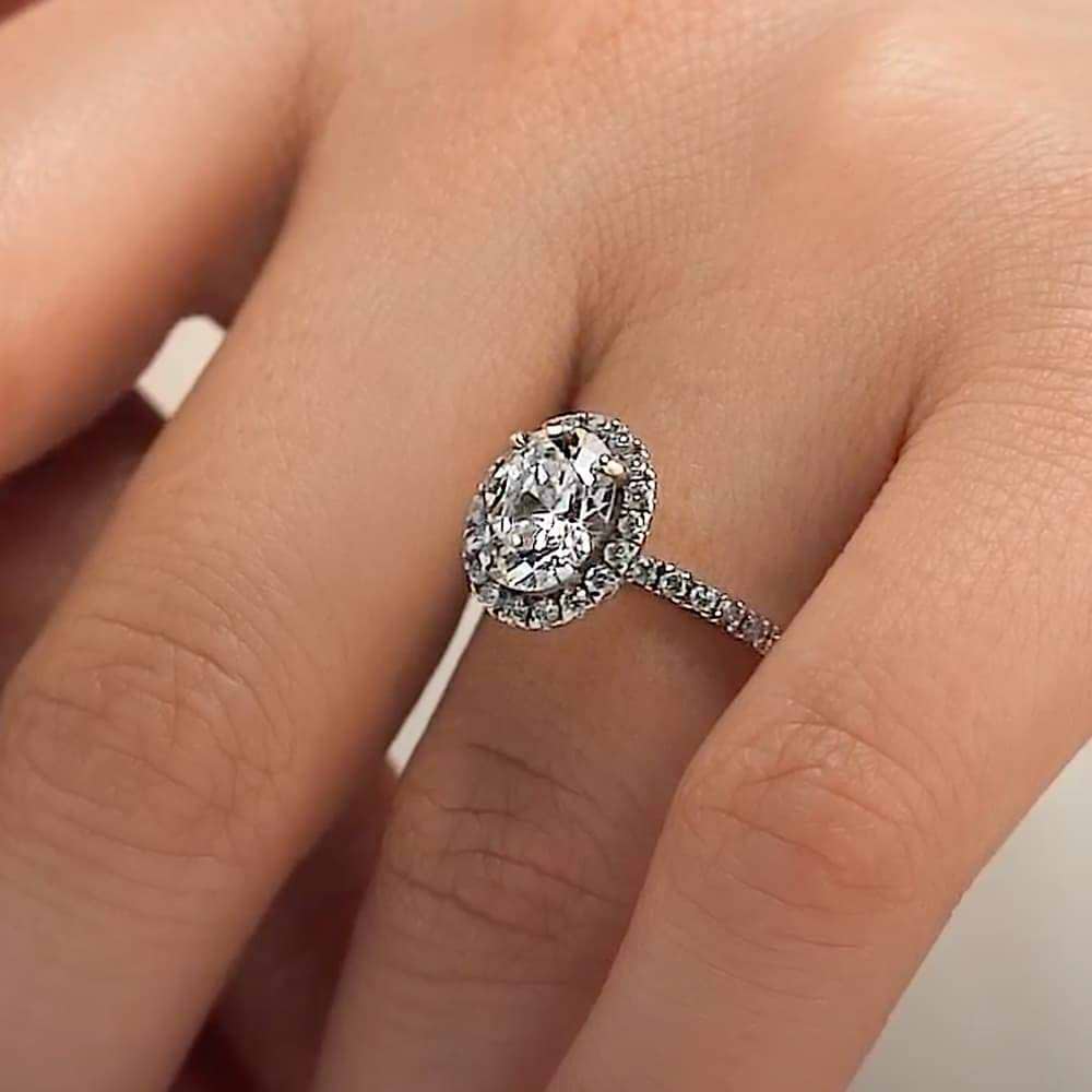 Shown with 1ct Oval Cut Lab Grown Diamond in Platinum|Dream diamond halo engagement ring with diamond accents and a 1ct oval cut lab grown diamond in platinum worn on hand