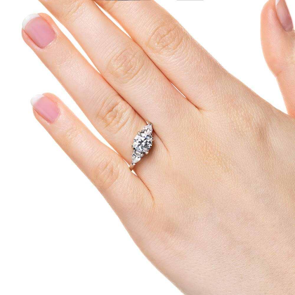 Shown with 1ct Round Cut Lab Grown Diamond Center Stone in 14k White Gold|Three stone engagement ring with 1ct round cut lab grown diamond center and 0.5ct pear cut diamond side stones in 14k white gold worn on hand