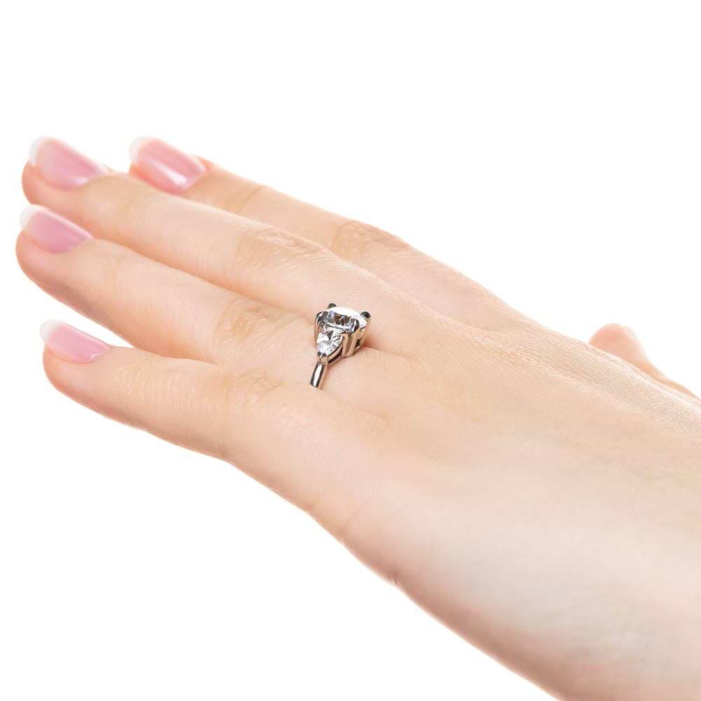Shown with 1ct Round Cut Lab Grown Diamond Center Stone in 14k White Gold|Three stone engagement ring with 1ct round cut lab grown diamond center and 0.5ct pear cut diamond side stones in 14k white gold worn on hand sideview
