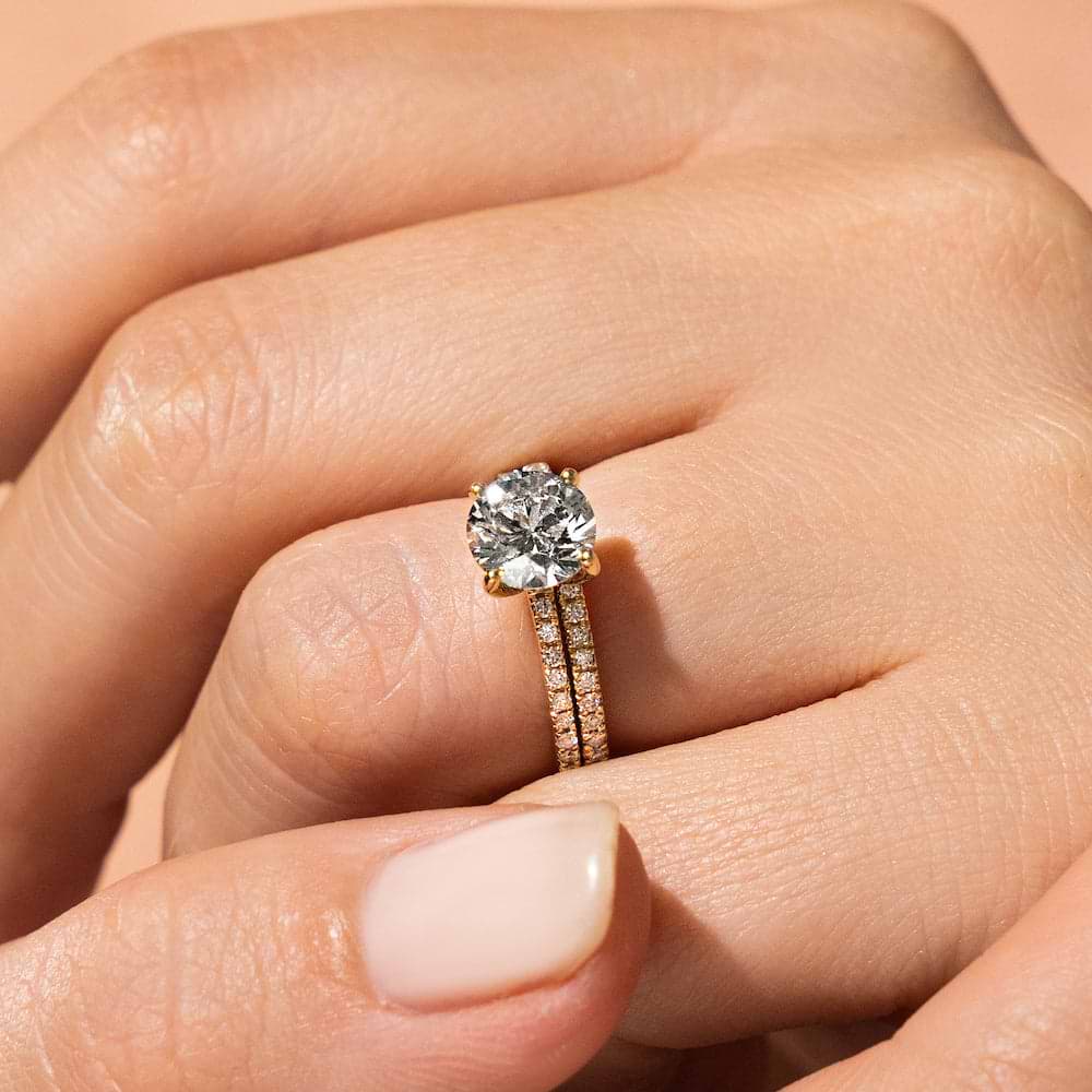 Shown with a 1.0ct Round cut Lab-Grown Diamond with accenting diamonds on the band in recycled 14K yellow gold with matching wedding band| diamond accented engagement ring Shown with a 1.0ct Round cut Lab-Grown Diamond with accenting diamonds on the band in recycled 14K yellow gold with matching wedding band