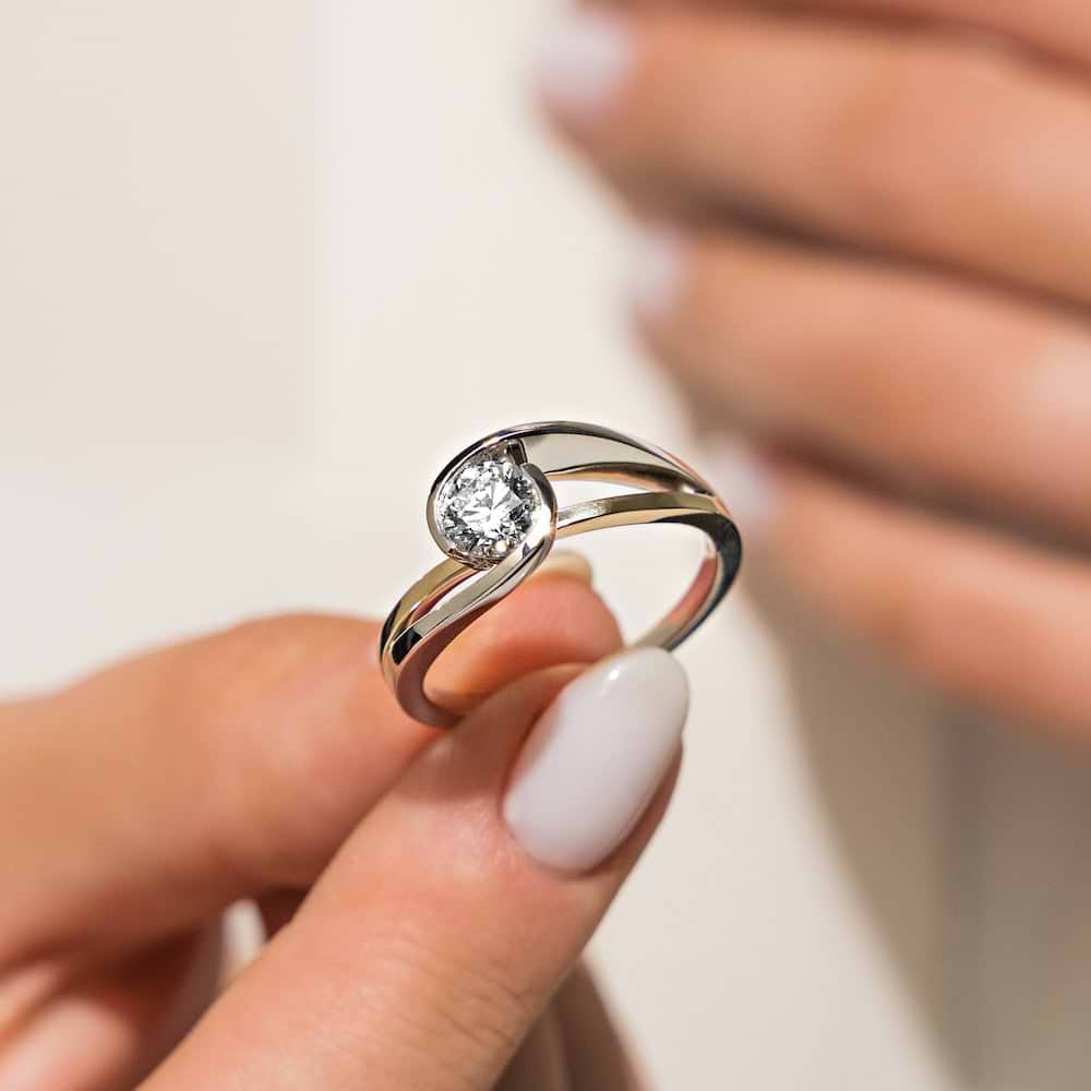Shown with 1ct Round Cut Lab Grown Diamond in Two Tone 14k White & Yellow Gold|Ethical modern two tone engagement ring with 1ct round cut lab grown diamond in a split shank 14k white gold and 14k yellow gold setting held in hand