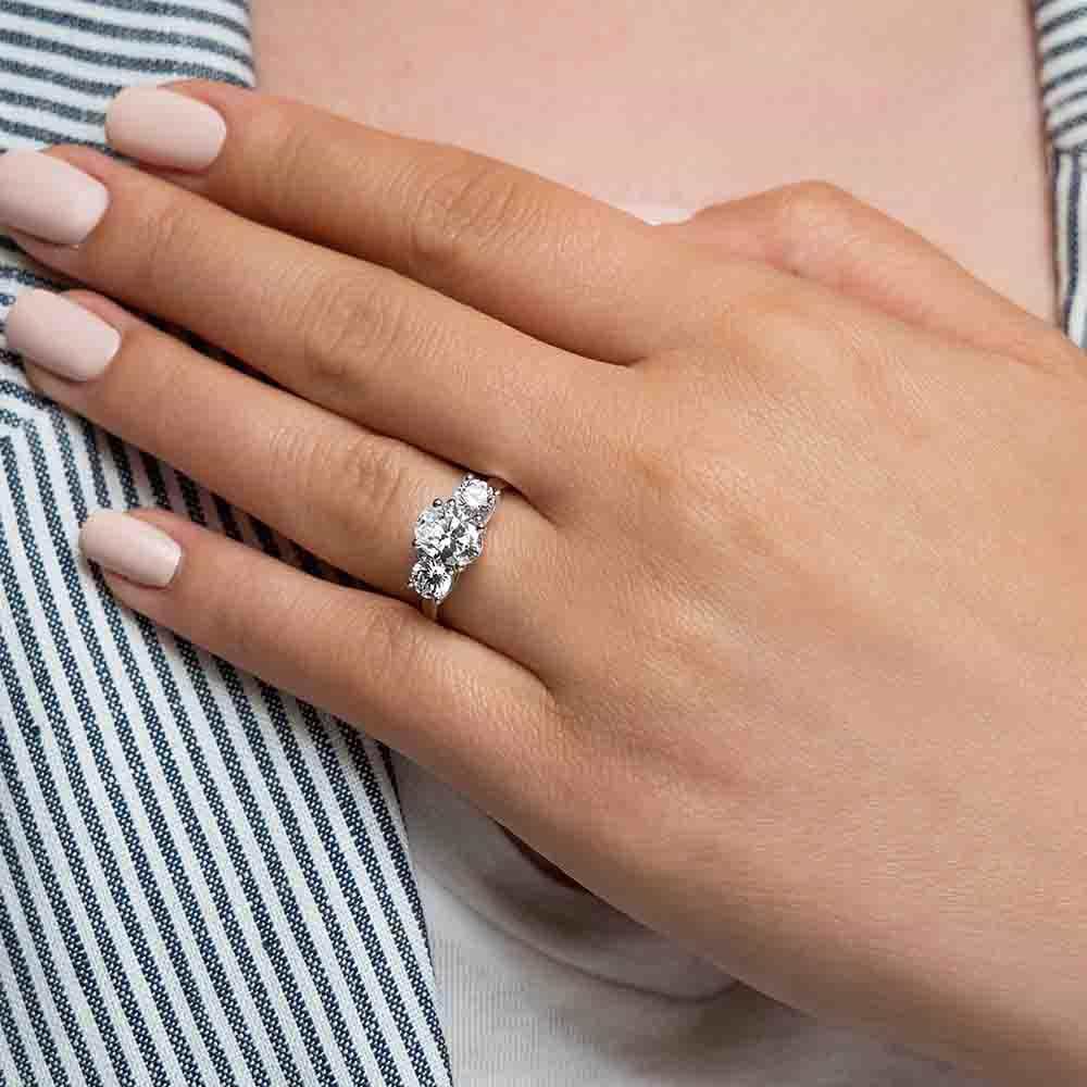Shown with 1ct Oval Cut and Two 0.5ct Round Cut Lab Grown Diamonds in 14k White Gold|Conflict free three stone engagement ring with 1ct oval cut lab grown diamond and two 0.5ct round cut lab diamond side stones in 14k white gold worn on hand