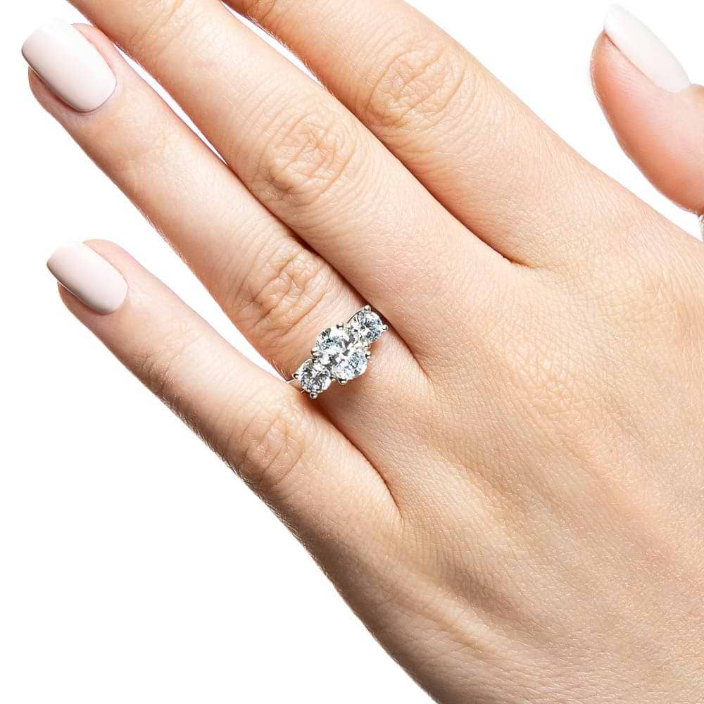 Shown with 1ct Oval Cut and Two 0.5ct Round Cut Lab Grown Diamonds in 14k White Gold|Three stone trellis set lab grown diamond engagement ring in white gold worn on hand