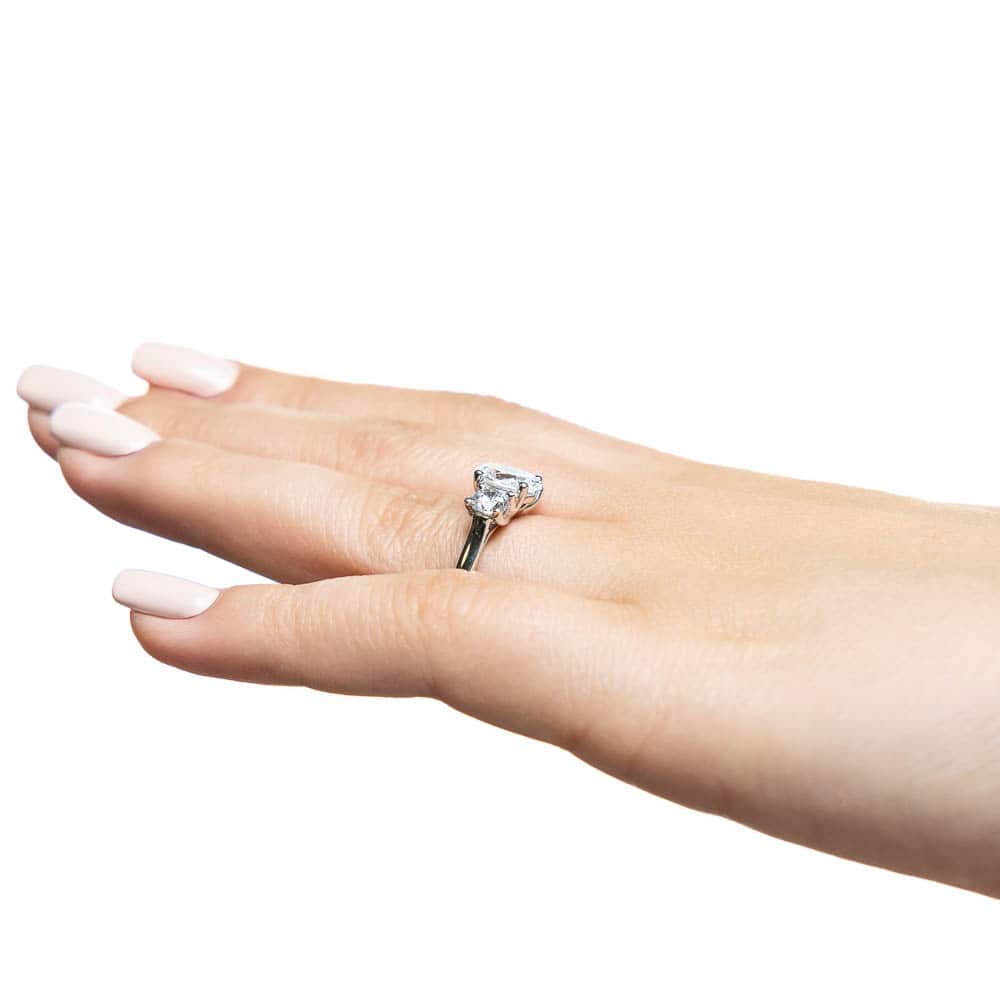 Shown with 1ct Oval Cut and Two 0.5ct Round Cut Lab Grown Diamonds in 14k White Gold|Three stone trellis set lab grown diamond engagement ring in white gold worn on hand sideview