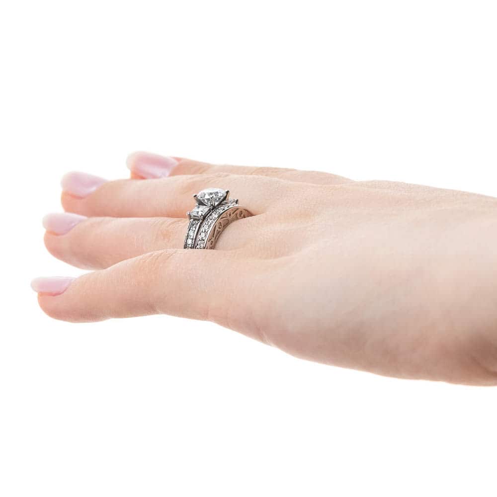 Shown with a Round cut center stone and two Princess cut Lab-Grown Diamonds side stones with scroll detailing and accenting diamonds on the band in recycled 14K white gold | three stone engagement ring Shown with round cut center stone and two Princess cut Lab-Grown Diamonds with scroll detailing and accenting diamonds on the band in recycled 14K white gold with matching wedding band