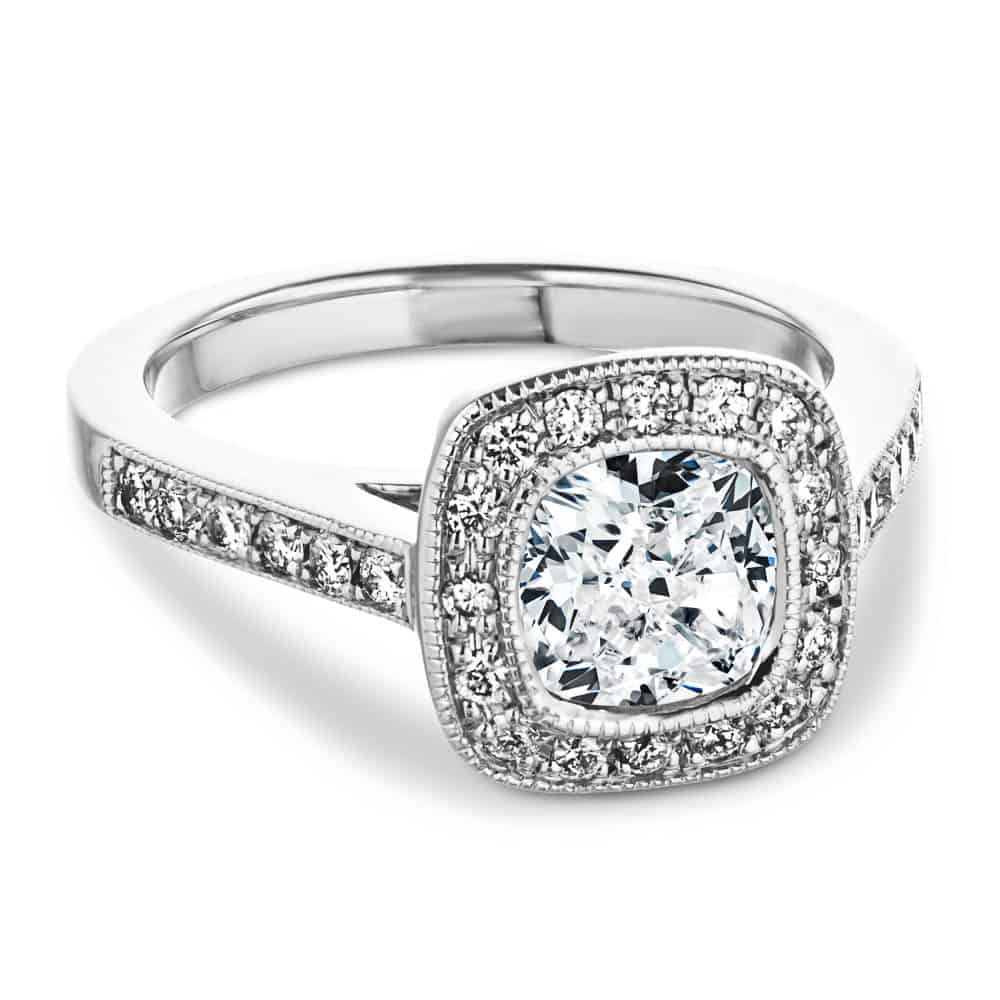 Shown with a 1.0ct Cushion cut Lab-Grown Diamond with a diamond accented and filigree detailed halo and accenting diamonds on the band in recycled 14K white gold 