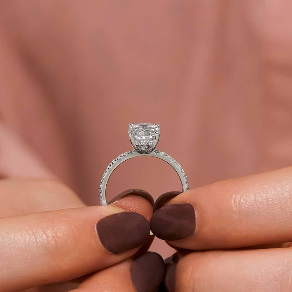 Shown with 1.5ct Oval Cut Lab Grown Diamond in 14k White Gold|Conflict-free diamond accented hidden halo engagement ring with 1.5ct oval cut lab grown diamond in 14k white gold held in hand