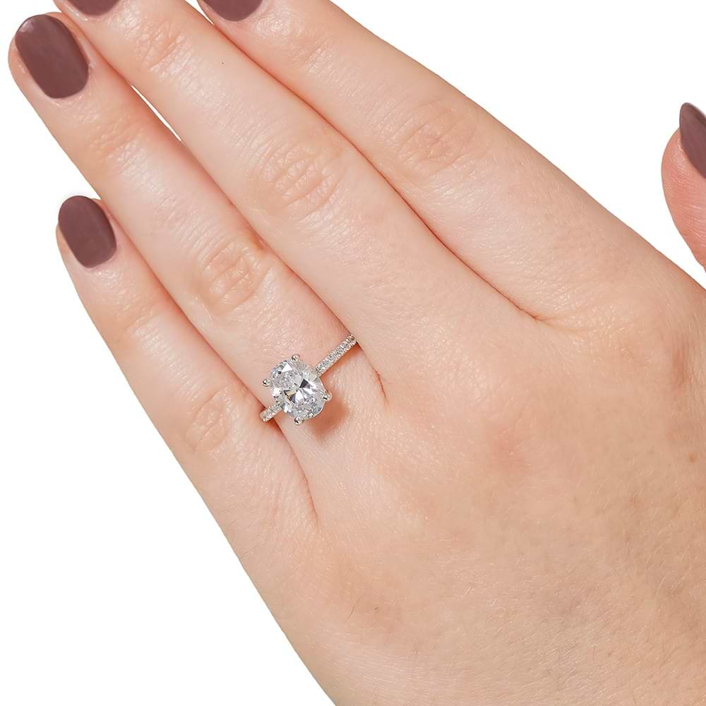 Shown with 1.5ct Oval Cut Lab Grown Diamond in 14k White Gold|Diamond accented hidden halo engagement ring with 1.5ct oval cut lab grown diamond in 14k white gold worn on hand