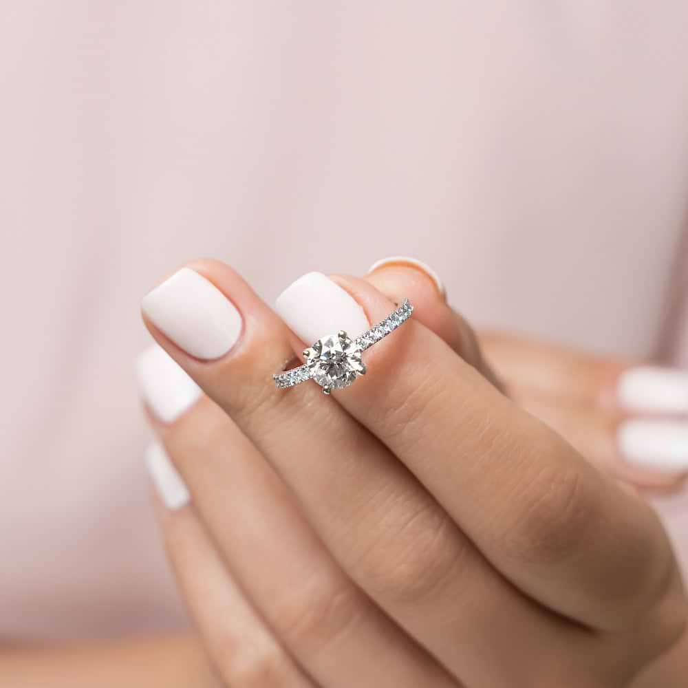 Shown with 1ct Round Cut Lab Grown Diamond in 14k White Gold|Stunning stackable diamond accented solitaire engagement ring with 1ct round cut lab grown diamond in 14k white gold held in hand
