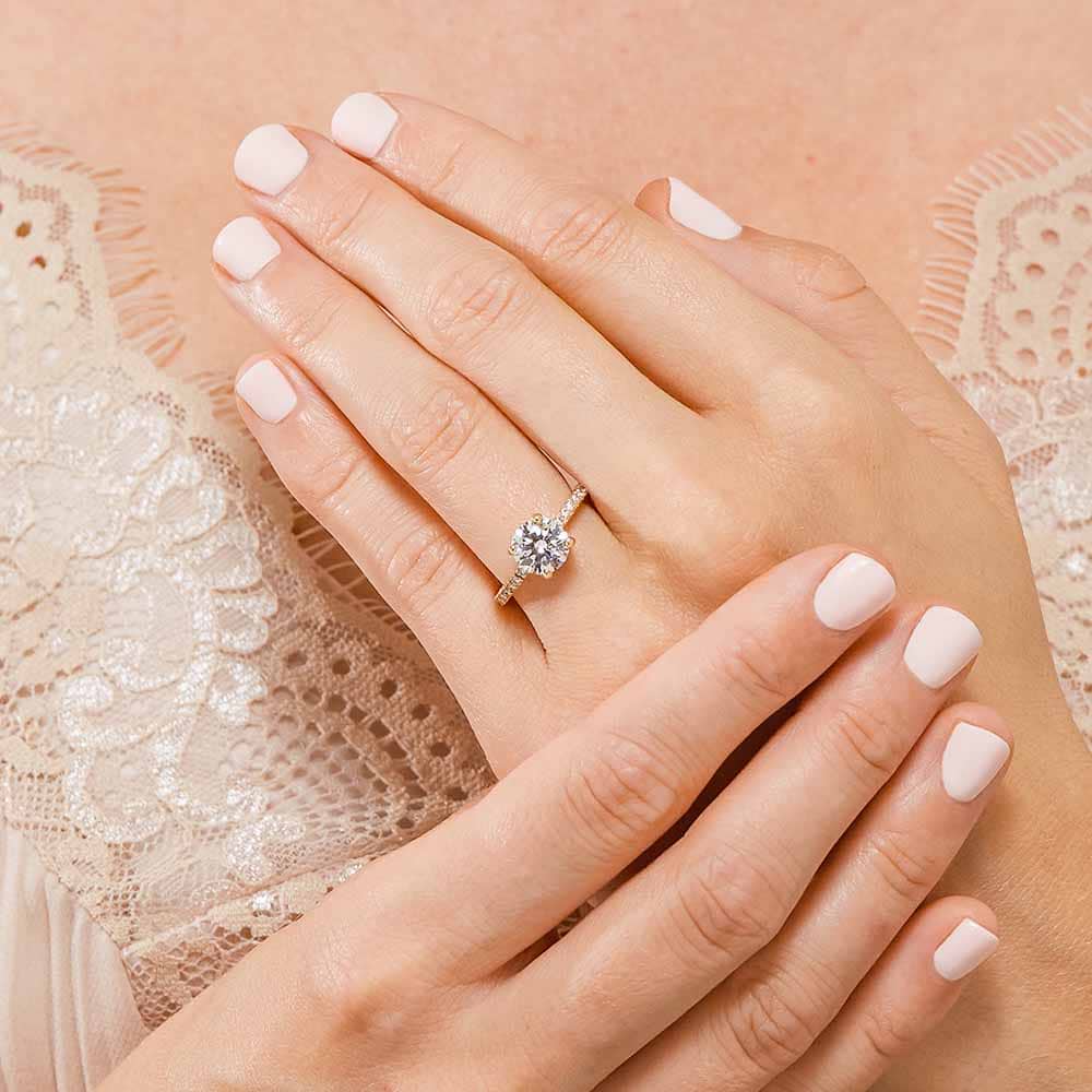 Shown with 1ct Round Cut Lab Grown Diamond in 14k Yellow Gold|Gorgeous conflict free diamond accented solitaire engagement ring with 1ct round cut lab grown diamond in 14k yellow gold worn on hand