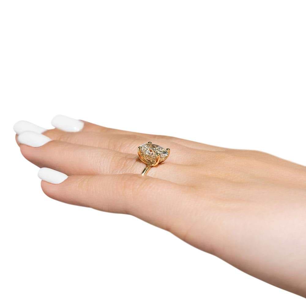 Shown with 3ct Oval Cut Lab Grown Diamond in 14k Yellow Gold|Elegant hidden halo engagement ring with 4 prong set 3ct oval cut lab grown diamond in a thin 14k yellow gold band worn on hand sideview