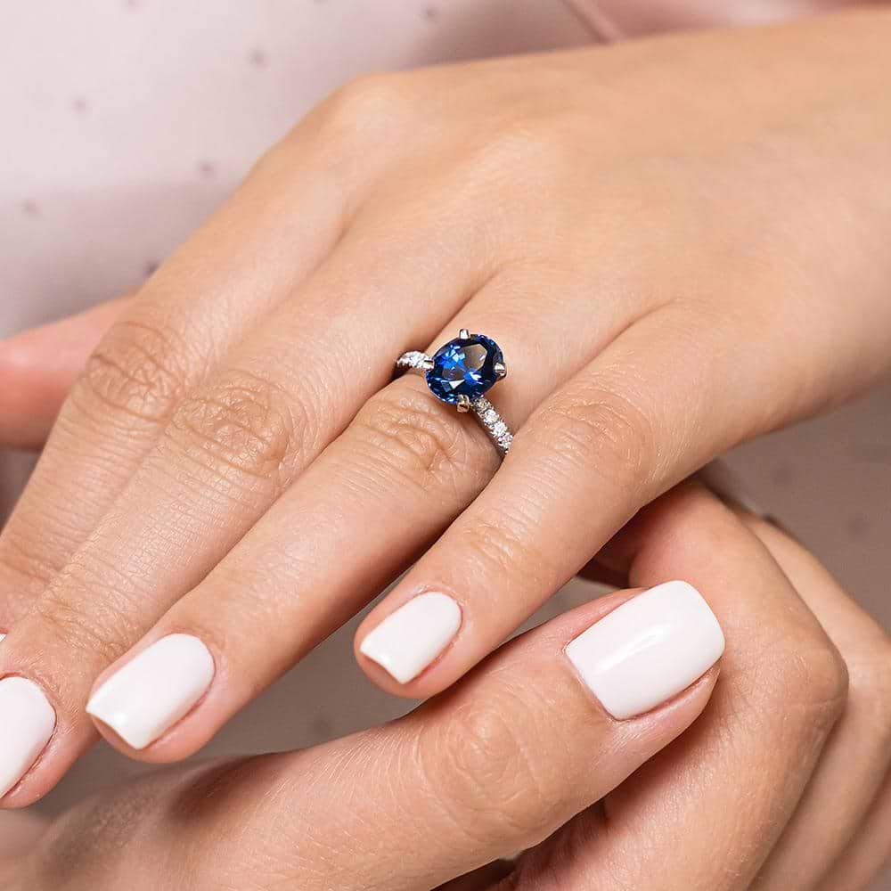 Shown with 2ct Oval Cut Lab Created Blue Sapphire in 14k White Gold|Beautiful diamond accented gemstone engagement ring with 2ct oval cut lab created blue sapphire center stone in 14k white gold worn on hand