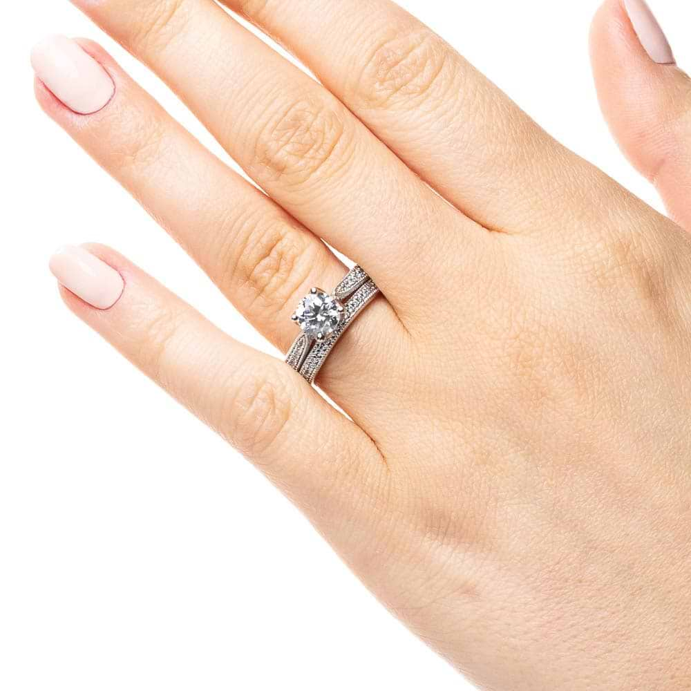 Shown with a 1.0ct Round cut Lab-Grown Diamond with diamonds accenting the band and filigree details in recycled 14K white gold with matching wedding band, can be purchased together for a discounted price