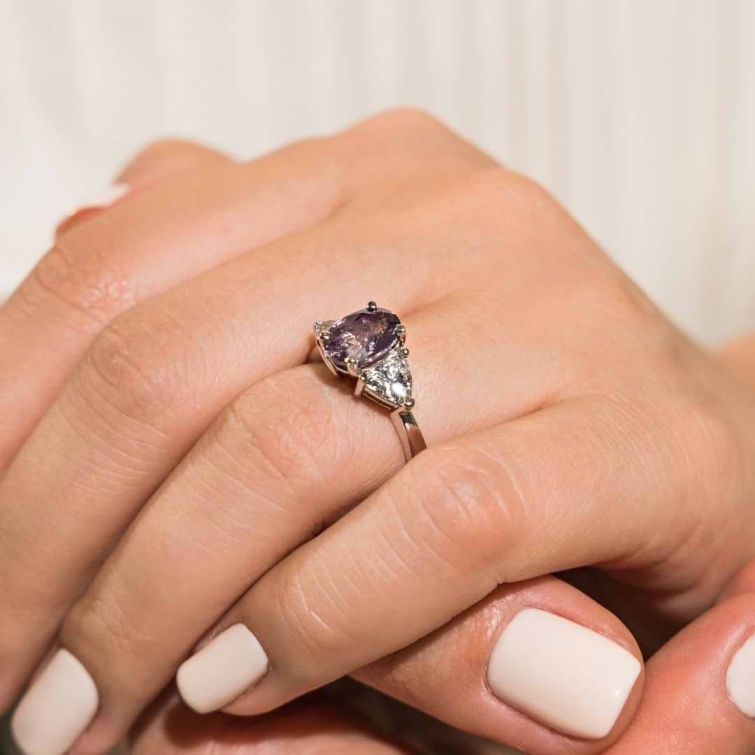 Shown with 1ct Oval Cut Lab Grown Alexandrite & 0.50ct Triangle Cut Side Stones in 14k White Gold|Unique three stone gemstone engagement ring with 1ct oval cut lab grown alexandrite and two 0.50 triangle cut diamond side stones in 14k white gold band shown worn on hand