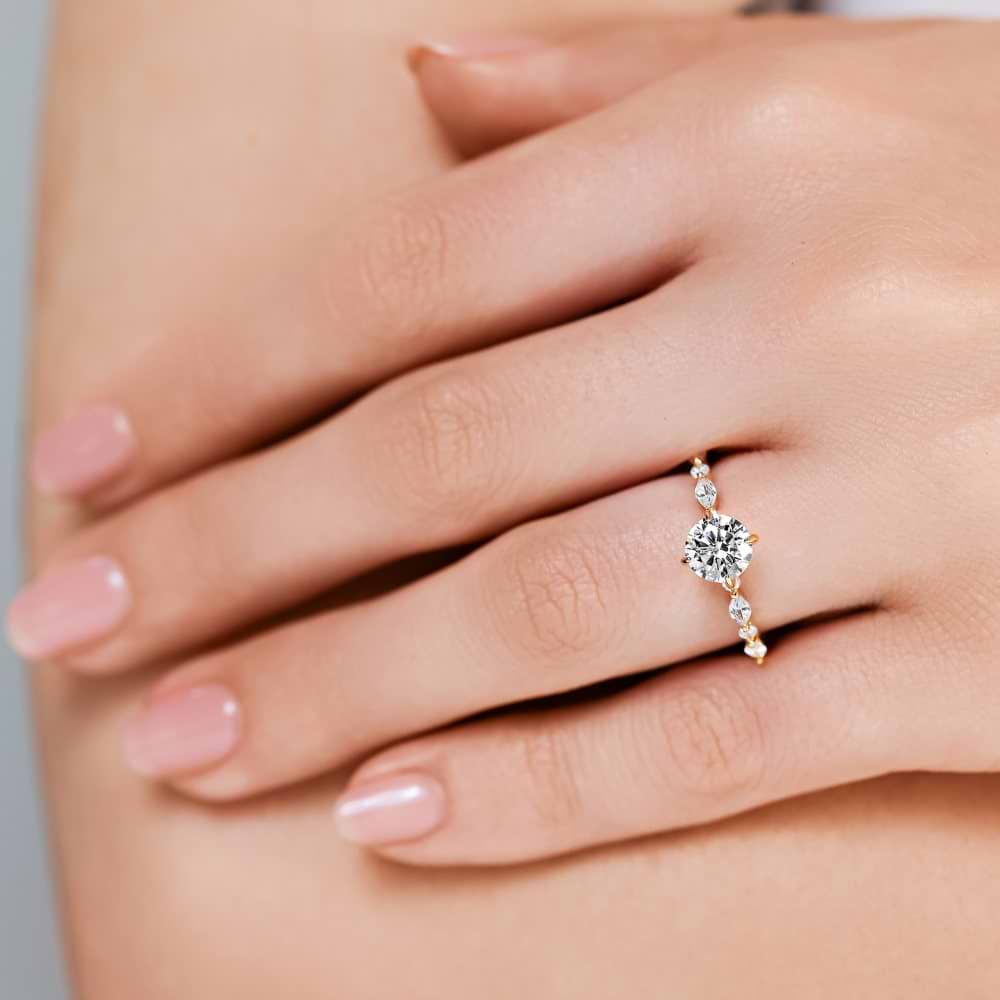 Shown here with a 1.0ct Round Cut center stone in 14K Yellow Gold|summer engagement ring with diamond accenting stones and a round cut center stone set in 14k yellow gold metal