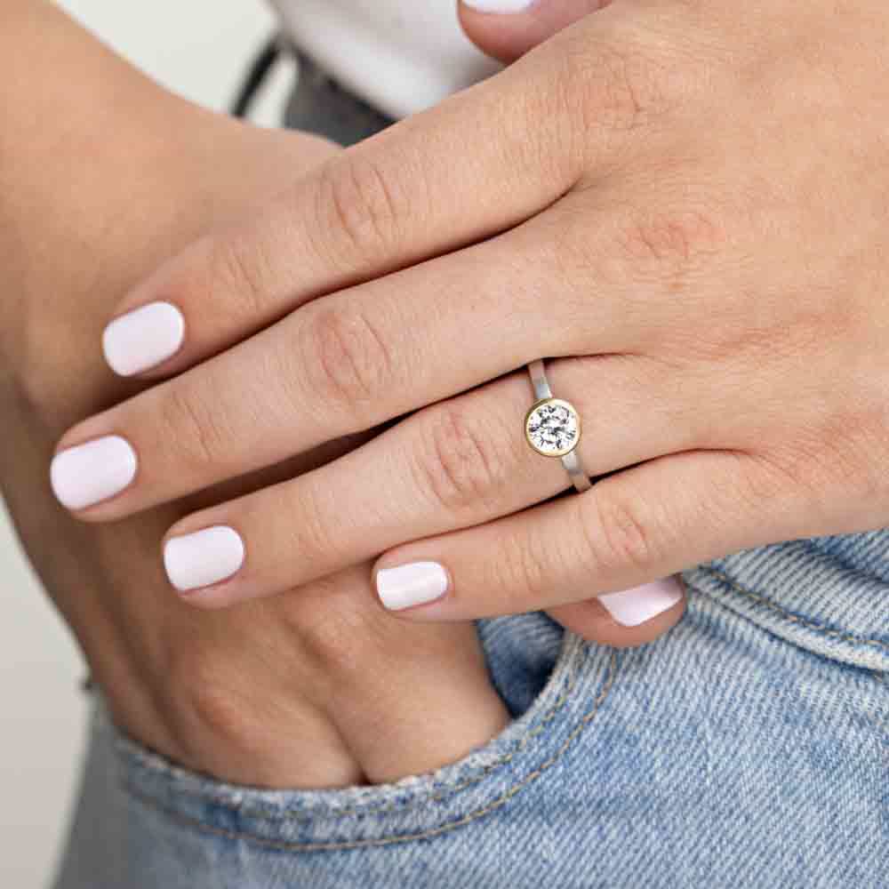 Shown in Two Toned 14K White Gold and 14K Yellow Gold|bezel set solitaire engagement ring with round cut lab grown diamond in satin finish two tone white gold and yellow gold metal