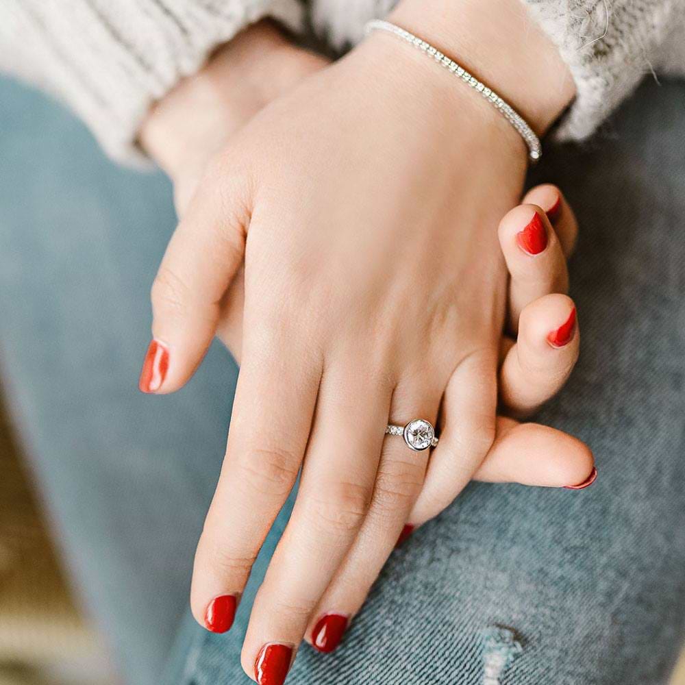Shown with a bezel set 1.0ct Round cut Lab-Grown Diamond with accenting stones on the band in recycled 14K white gold | stackable engagement ring Shown with a bezel set 1.0ct Round cut Lab-Grown Diamond with accenting stones on the band in recycled 14K white gold