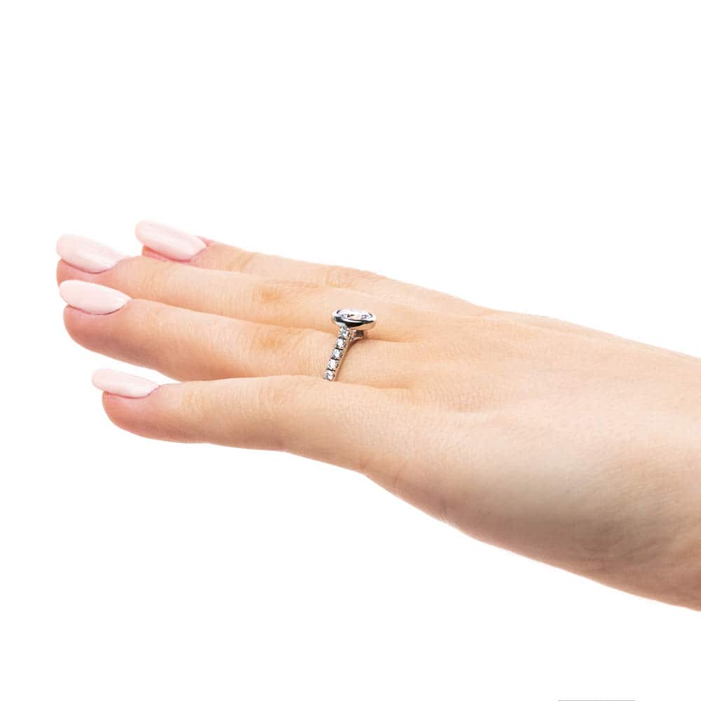 Shown with a bezel set 1.0ct Round cut Lab-Grown Diamond with accenting stones on the band in recycled 14K white gold | stackable engagement ring Shown with a bezel set 1.0ct Round cut Lab-Grown Diamond with accenting stones on the band in recycled 14K white gold