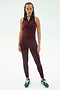 A woman faces forward in SPLITS59's Amber Airweight High Waist 7/8 leggings and top in Dark Cherry/Indigo, crafted from soft nylon spandex, paired with navy sneakers against a white background.