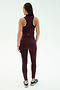A woman faces away, wearing the SPLITS59 Amber Airweight High Waist 7/8 leggings in Dark Cherry/Indigo, paired with a matching sleeveless top and black-and-white sneakers against a plain light background.