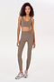 A woman wearing a beige sports bra and ultra luxe fabric, high waist Ella Airweight 7/8 leggings in Lentil/Black by SPLITS59.