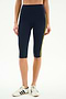 A person wears SPLITS59 Ella High Waist Airweight Capri in Indigo/Bright Yellow, perfect for hot yoga, paired with white sneakers with black stripes, against a white background.