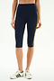 A person wears SPLITS59 Ella High Waist Airweight Capri in Indigo/Bright Yellow, perfect for hot yoga, paired with white sneakers with black stripes, against a white background.