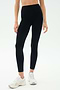 A person in SPLITS59 Emerson Airweight High Waist leggings in Black/Ice and white sneakers stands against a plain light background, ready for Pilates or hot yoga.
