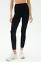 A person in SPLITS59 Emerson Airweight High Waist leggings in Black/Ice and white sneakers stands against a plain light background, ready for Pilates or hot yoga.