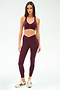 Woman wearing the SPLITS59 Mia Rigor Bra in Dark Cherry with matching leggings and beige sneakers, standing against a plain light background.