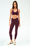 Woman wearing the SPLITS59 Mia Rigor Bra in Dark Cherry with matching leggings and beige sneakers, standing against a plain light background.