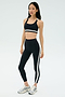 On a white background, a person wears the SPLITS59 Miles Rigor Bra - Black/White with matching striped leggings and silver athletic shoes—ideal for gym workouts and optimal support.