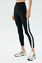 Wearing SPLITS59’s Miles High Waist Rigor 7/8 leggings in Black/White with side stripes and silver running shoes, this look is perfect for gym sessions or active days against a minimal background.